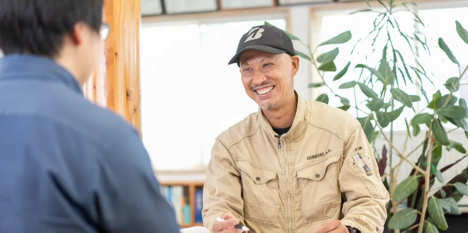 向かいに座る人物と対話しており、打ち合わせや面談の場面を思わせる構図