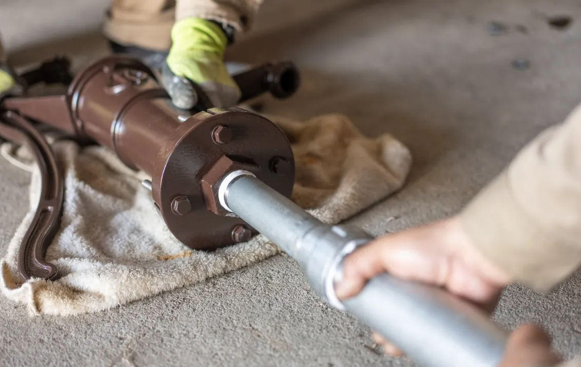 作業員が手袋を着用し、大型の金属製配管部品を組み立てている様子