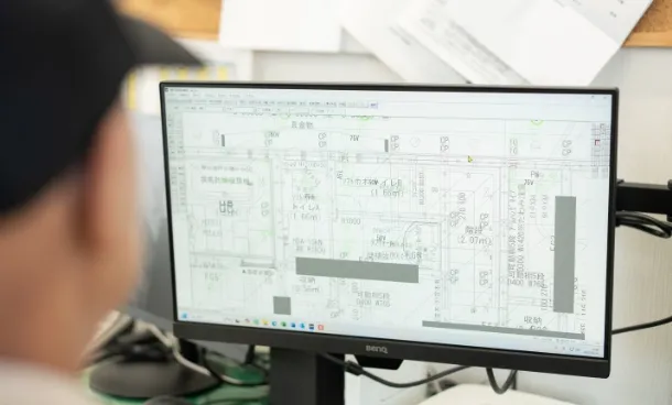 モニターの前に人物が座っており、図面データを確認・編集している場面